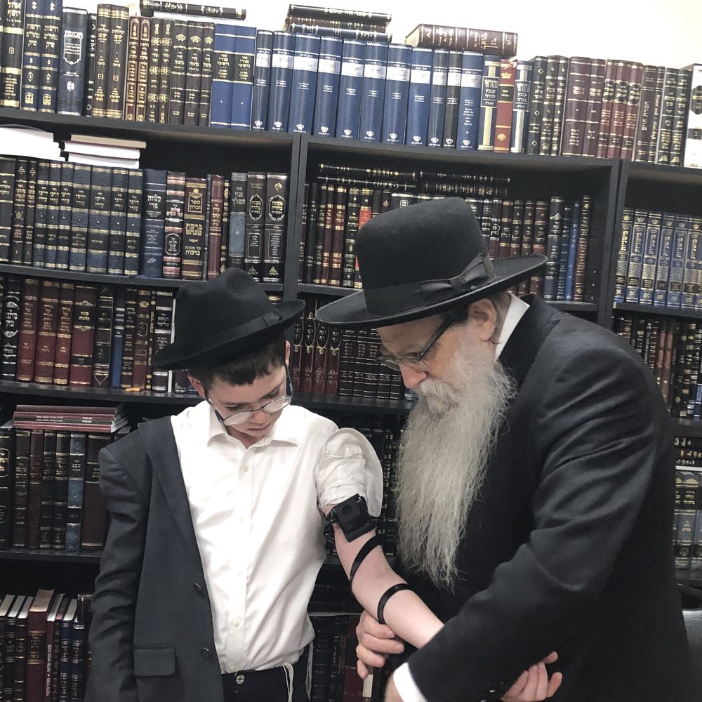 Shloimy being helped with tefillin
